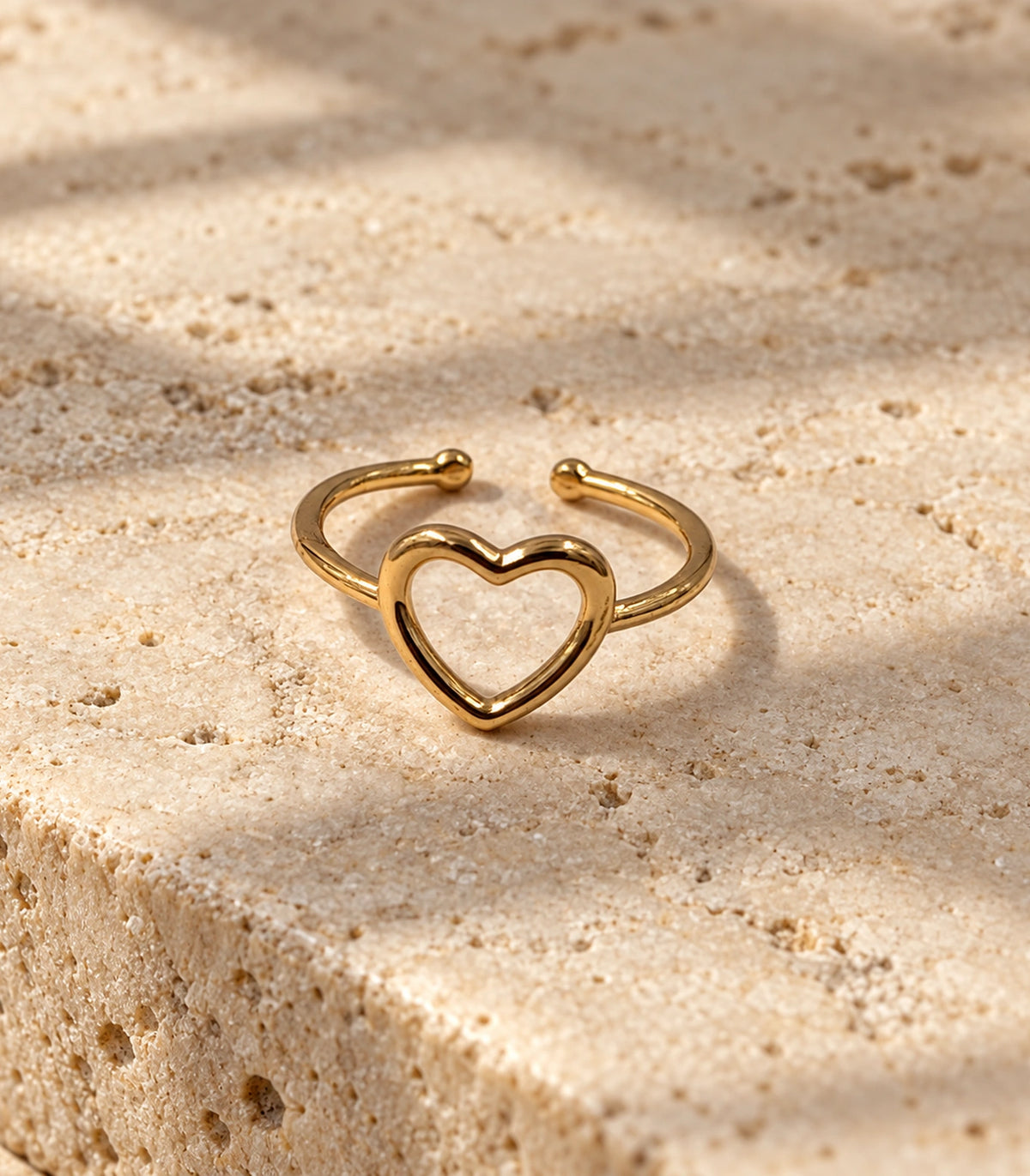 Single gold open heart ring with open back on a stone surface