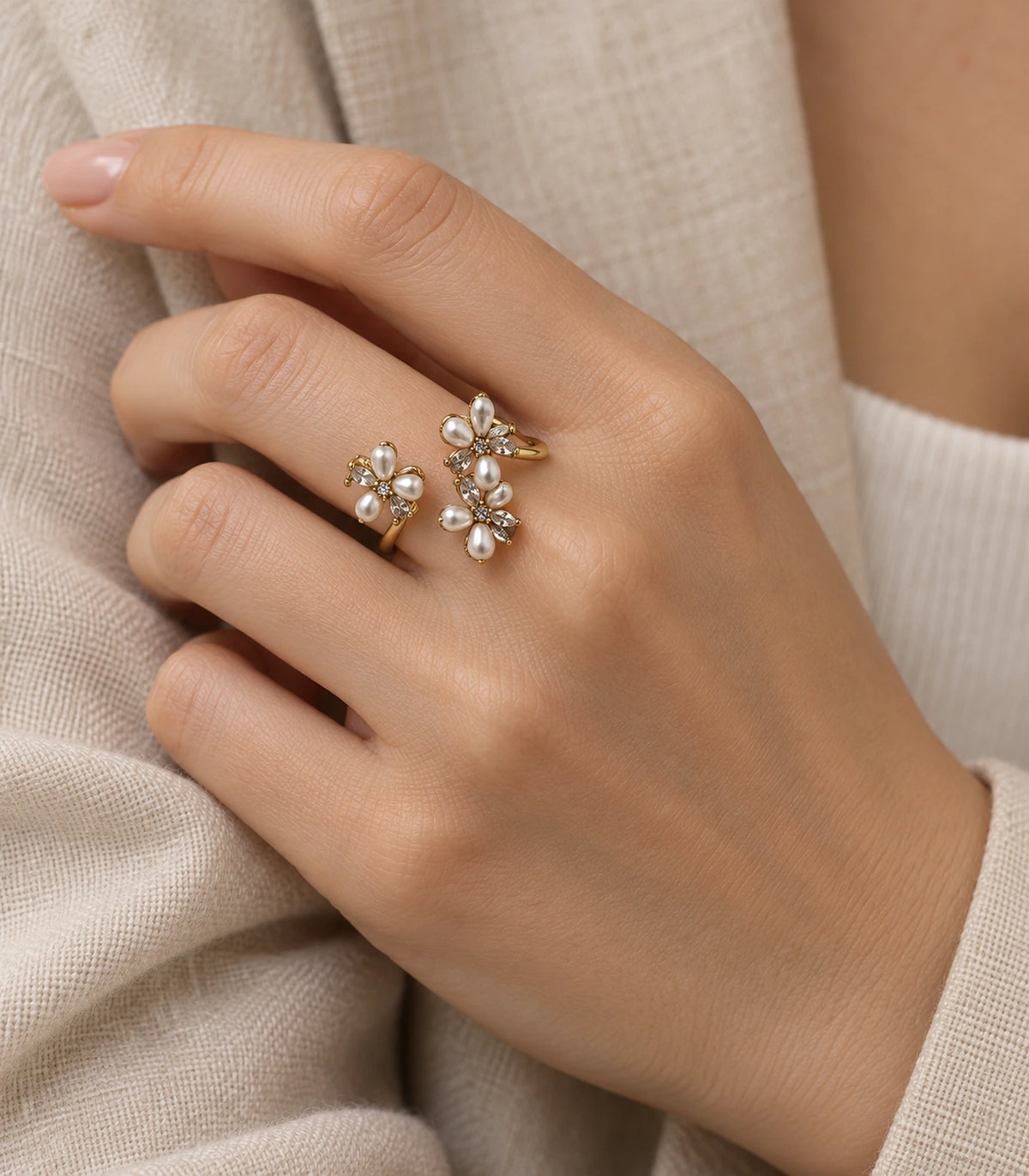 Botanical open ring worn on a bent hand beside a cream sleeve