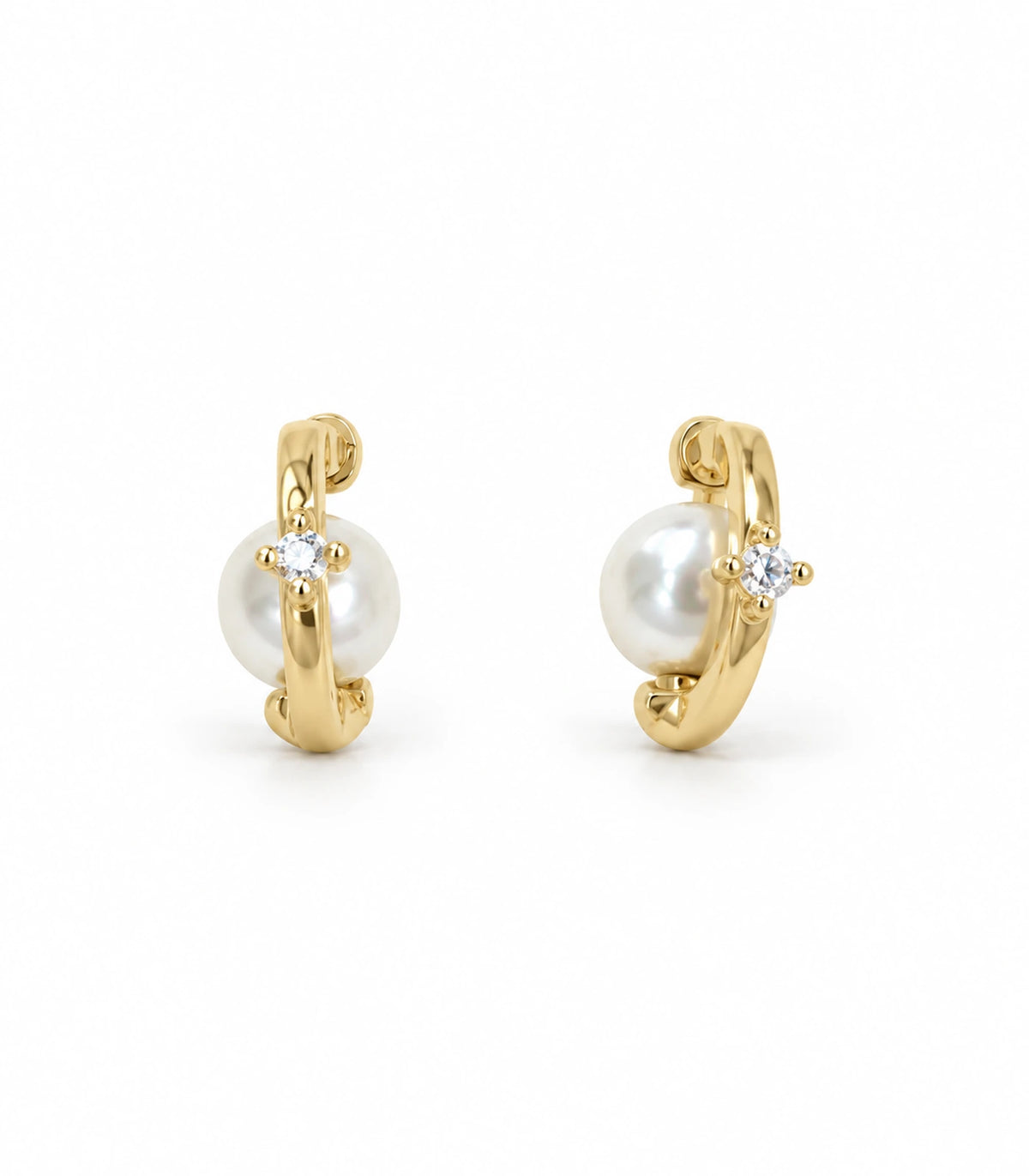 Matching pair of gold-tone orbit huggie earrings, each with one pearl-style accent and one clear stone, on white
