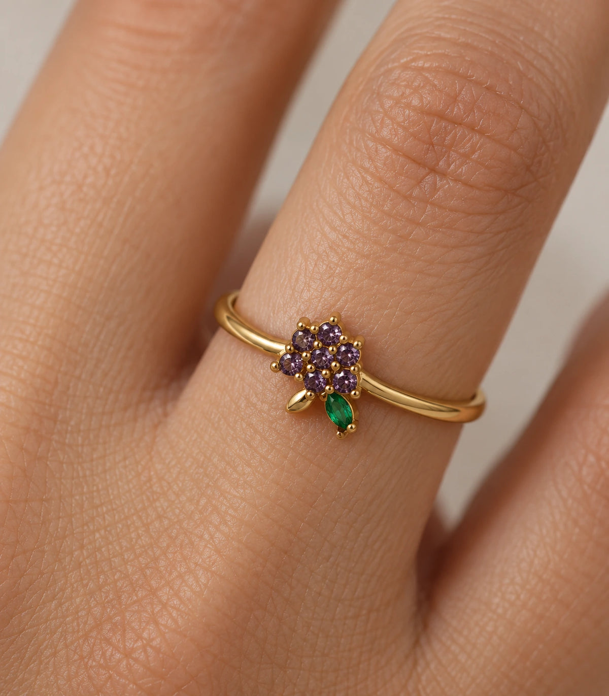 Close-up of the seven purple stones and green leaf ring worn on a finger
