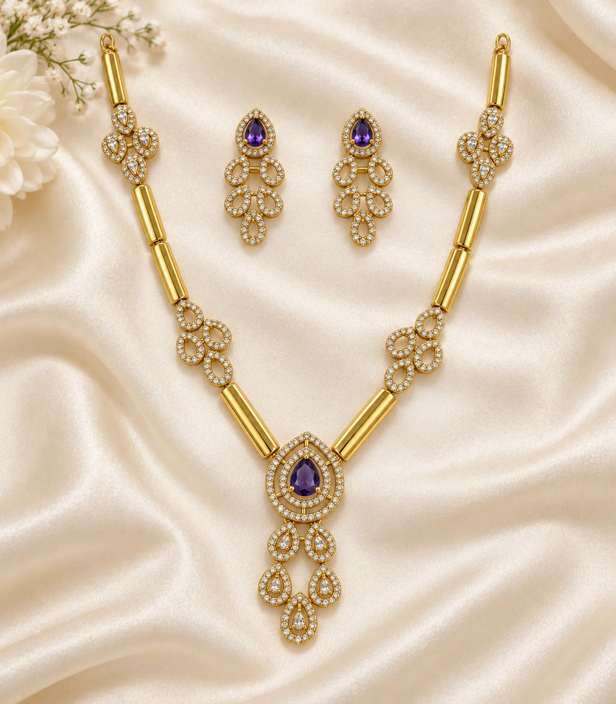 Complete gold-tone purple teardrop necklace and matching pair of earrings on ivory fabric
