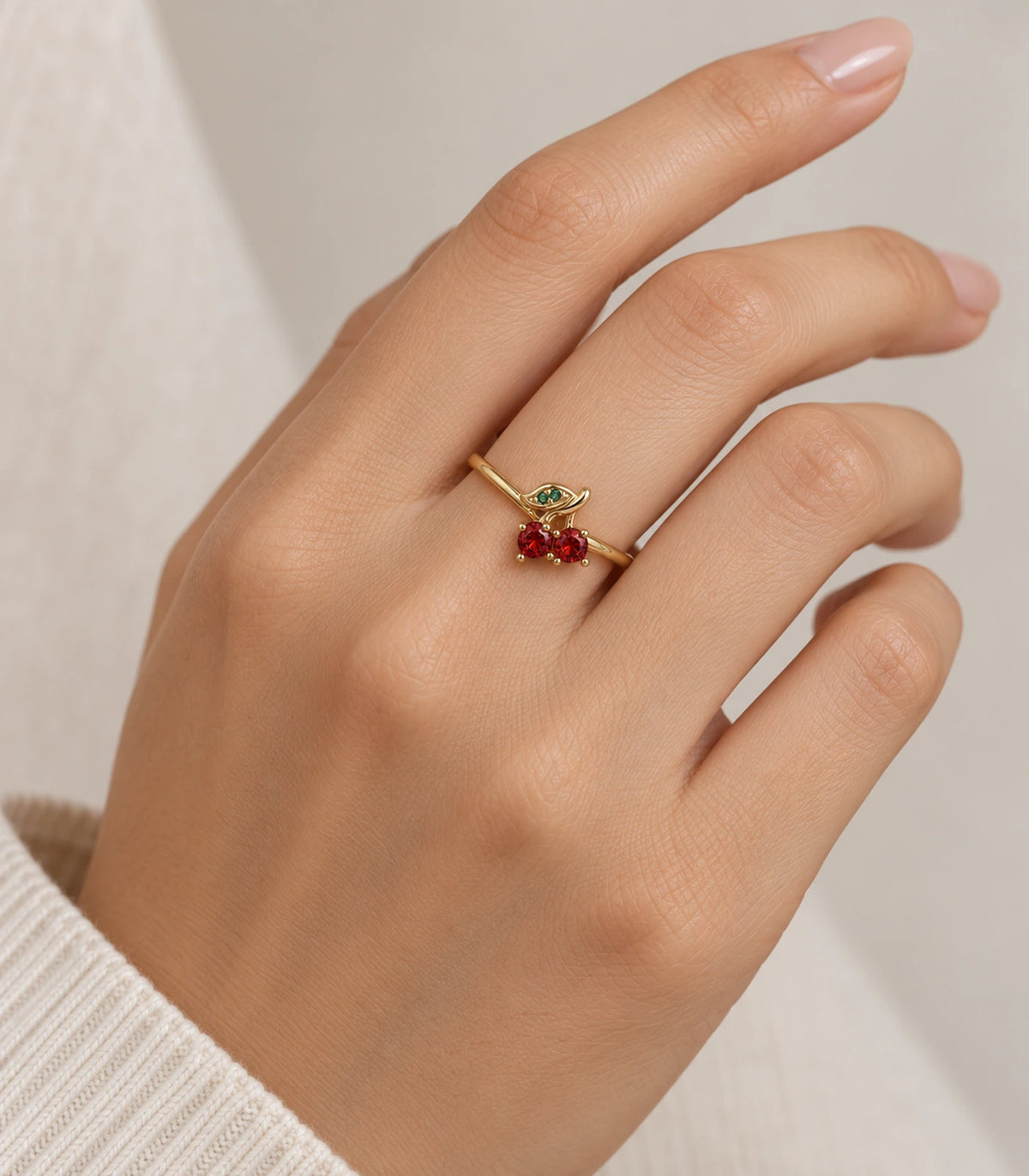 Gold-tone red cherry and green leaf ring worn on a hand