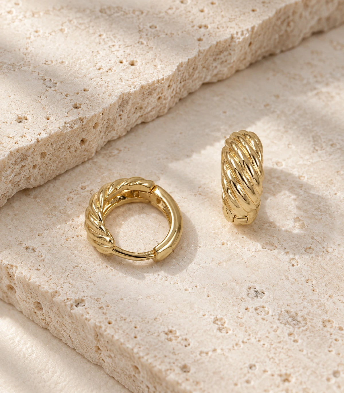 JIMIKI Twisted Rope Huggie Earrings in Gold Tone — editorial flat lay #color_gold-tone