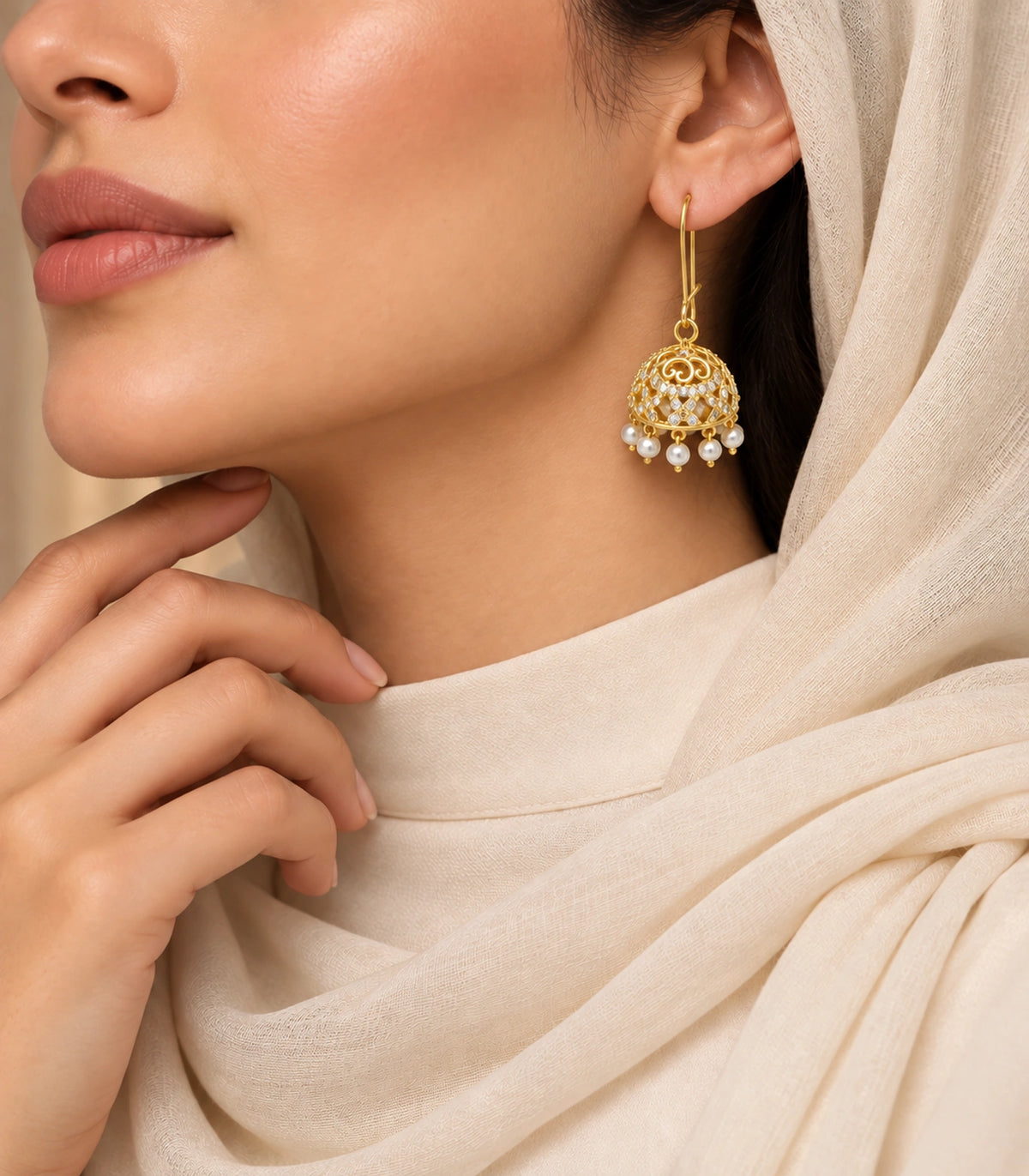 Gold Scrollwork Crystal Jhumka Earrings in Gold — earring worn with a cream scarf, face cropped below the eyes #color_gold