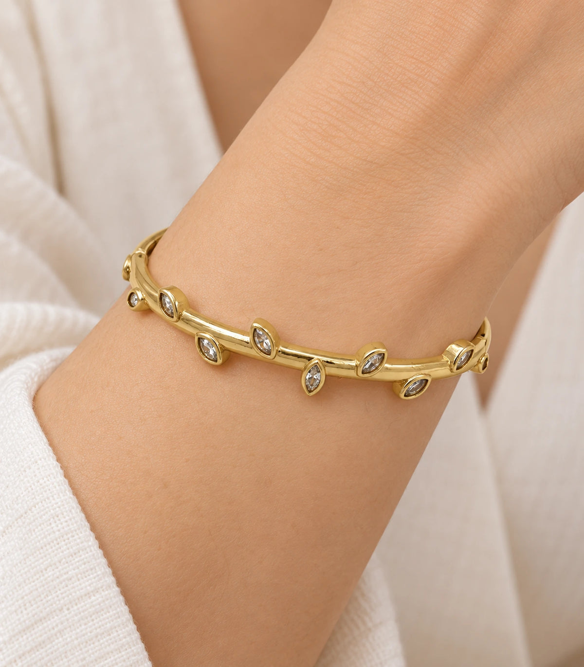 JIMIKI Gold-Tone Alternating Marquise Crystal Bangle — close-up of the bangle worn on the wrist #color_gold-tone / clear