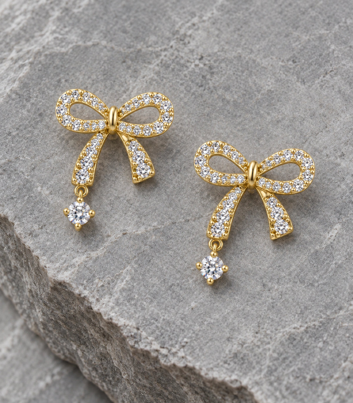 JIMIKI Gold-Tone Asymmetric Crystal Bow Round Drop Stud Earrings in Gold Tone, editorial flat lay