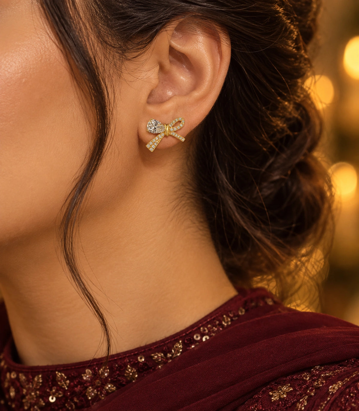 JIMIKI Gold-Tone Asymmetric Crystal Bow Stud Earrings in Gold / Clear, editorial model view