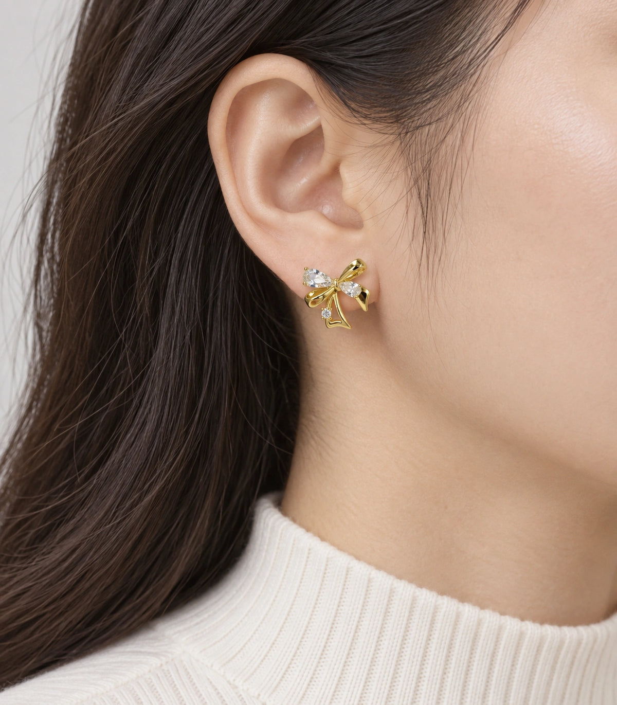 JIMIKI Asymmetric Crystal Bow Stud Earring Pair in Gold / Clear, model wearing view #color_gold / clear