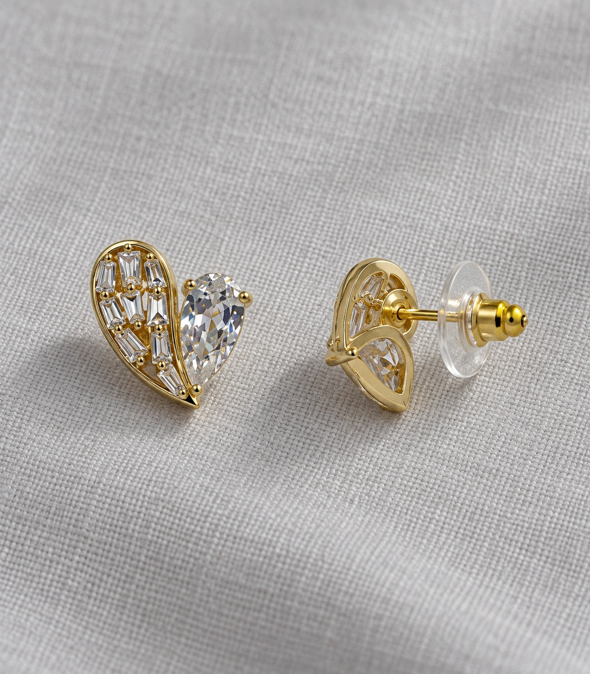 JIMIKI Asymmetric Crystal Heart Stud Earring Pair in Gold Tone, editorial flat lay #color_gold tone