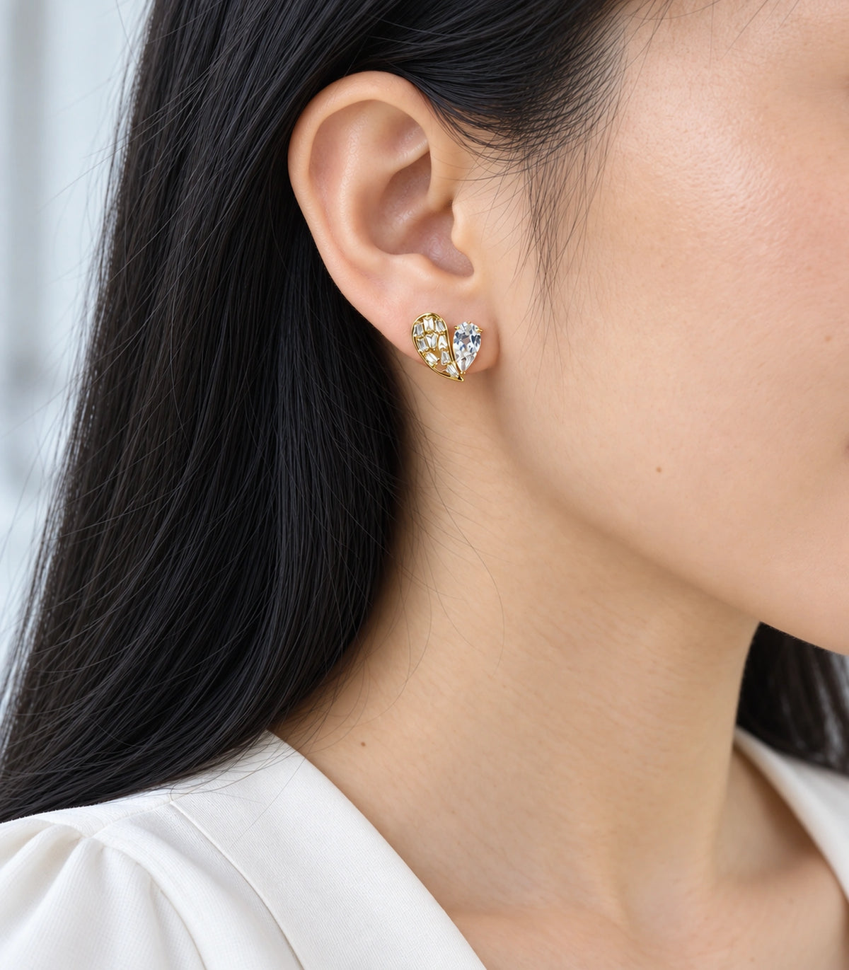 JIMIKI Asymmetric Crystal Heart Stud Earring Pair in Gold Tone, model wearing view #color_gold tone