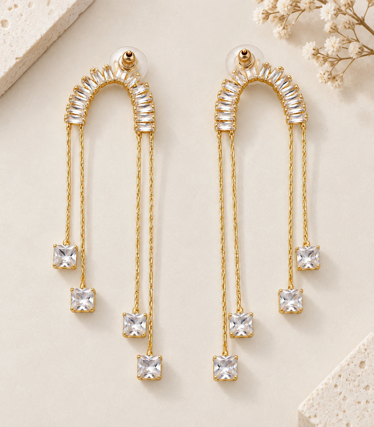 JIMIKI Gold-Tone Crescent Crystal Chain Drop Earrings — pair in a styled flat lay #color_gold-tone / clear