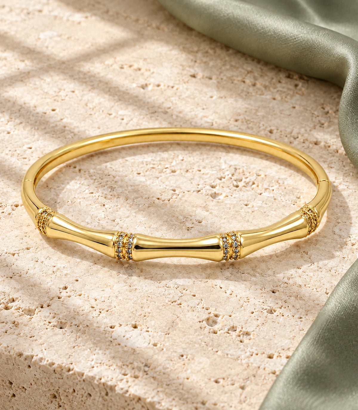JIMIKI Gold-Tone Bamboo Crystal Collar Bangle — bangle in a styled flat lay #color_gold-tone / clear