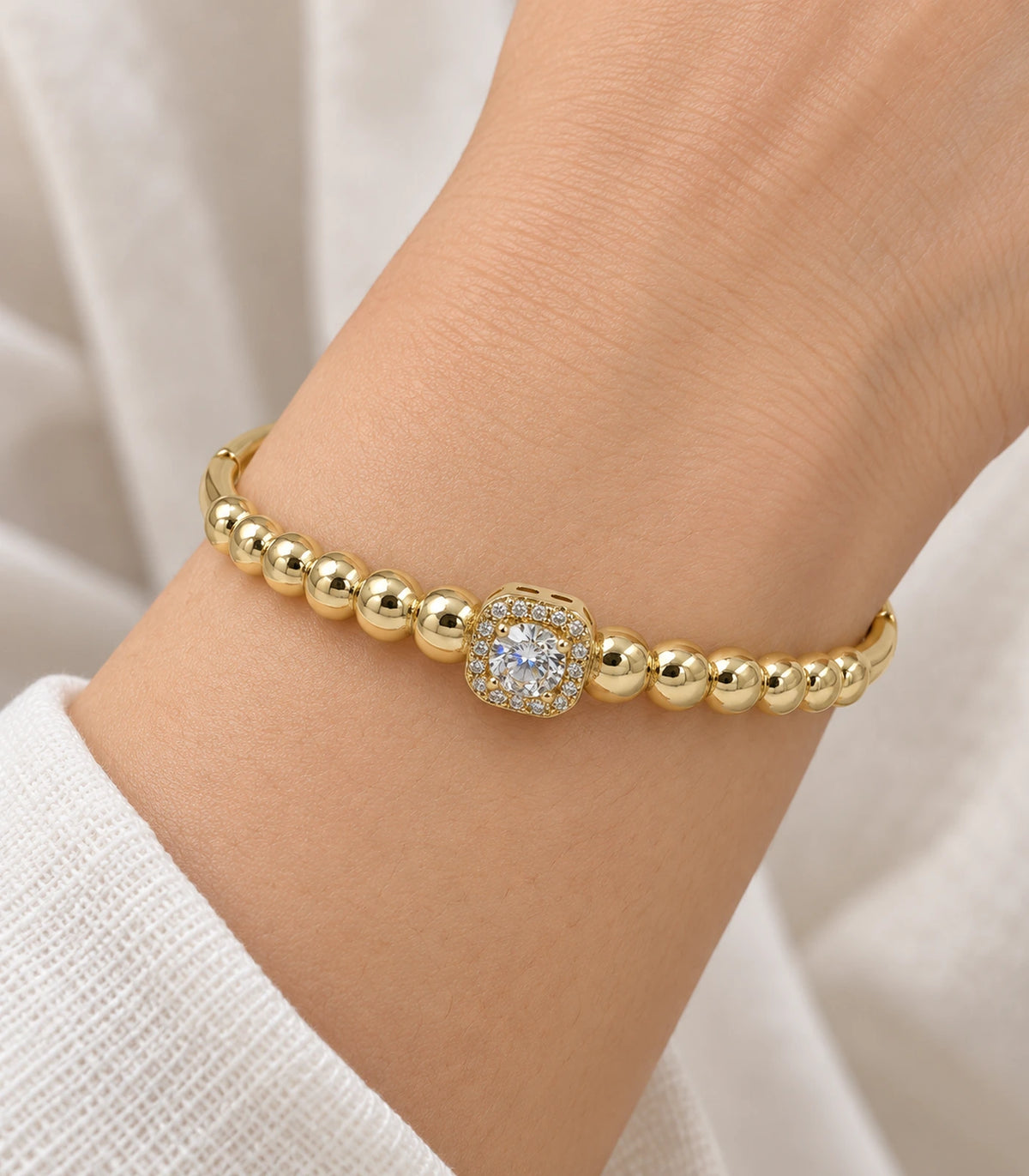 JIMIKI Gold-Tone Beaded Square Halo Bangle — close-up of the bangle worn on the wrist #color_gold-tone / clear