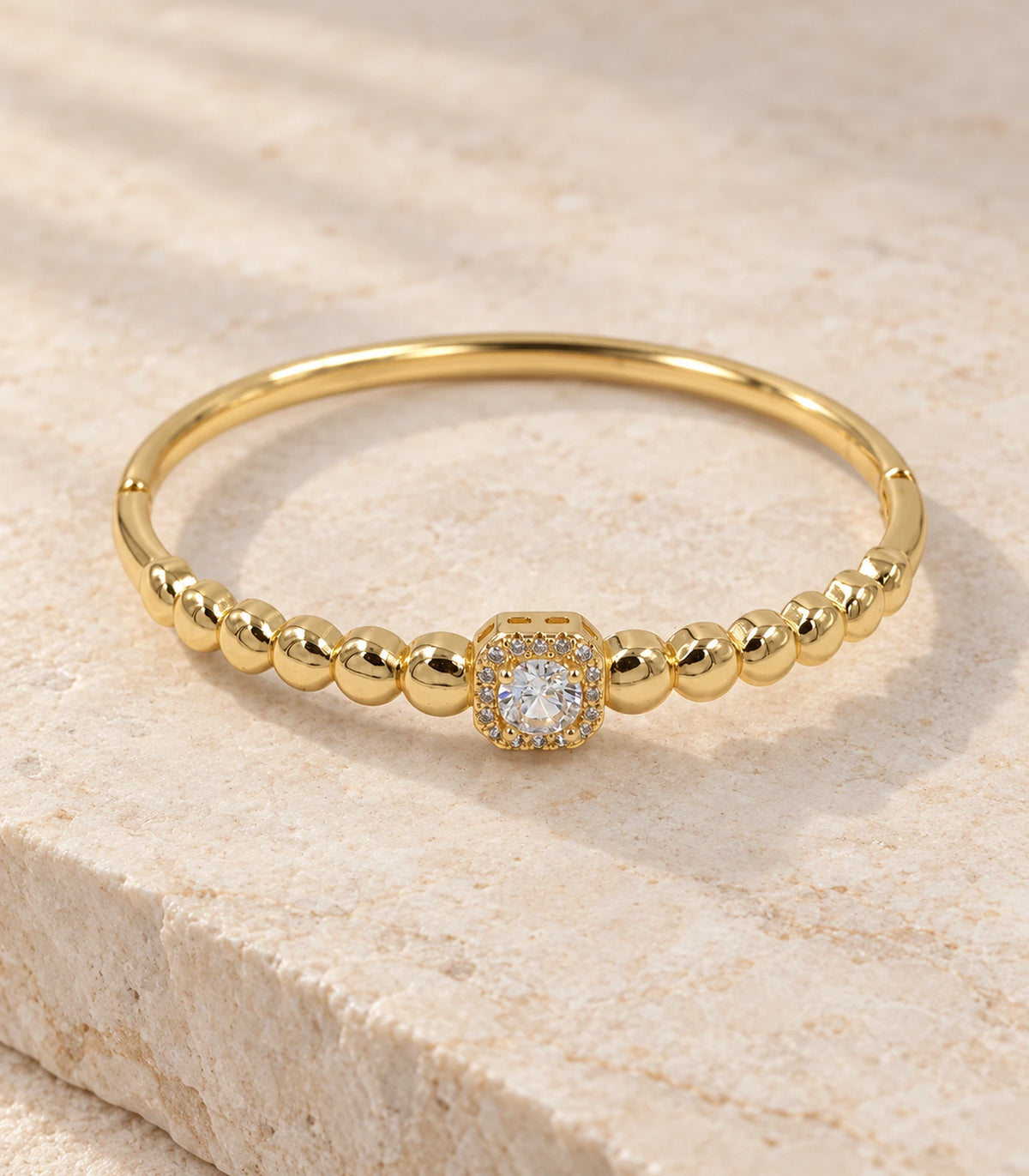 JIMIKI Gold-Tone Beaded Square Halo Bangle — bangle in a styled flat lay #color_gold-tone / clear