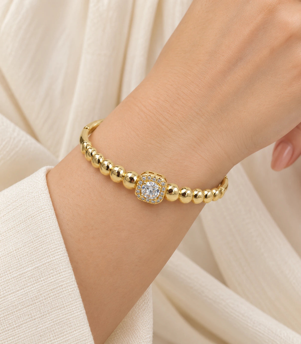 JIMIKI Gold-Tone Beaded Square Halo Bangle — worn on the wrist #color_gold-tone / clear