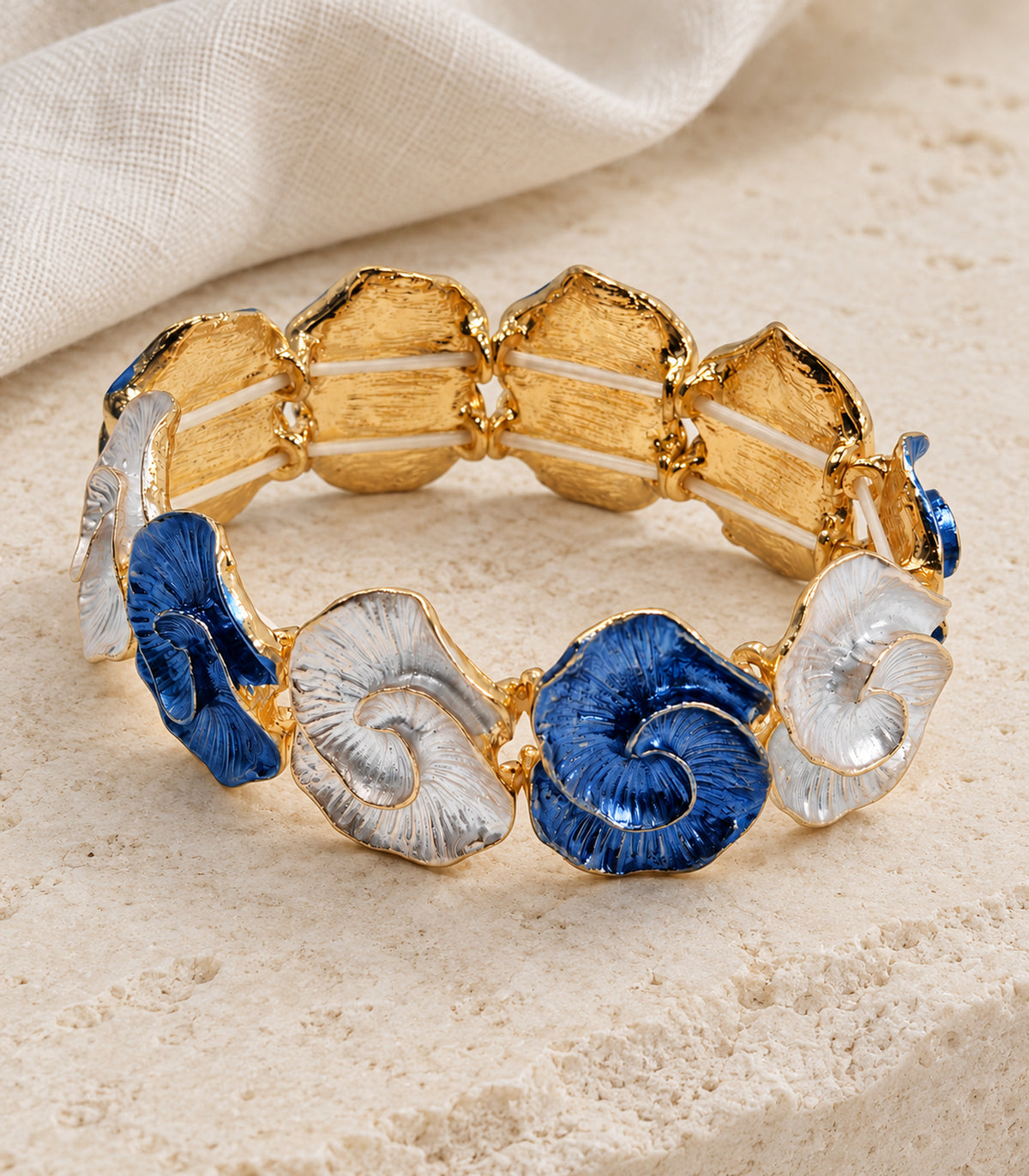 Gold-tone blue and white spiral-shell bracelet — editorial flatlay view