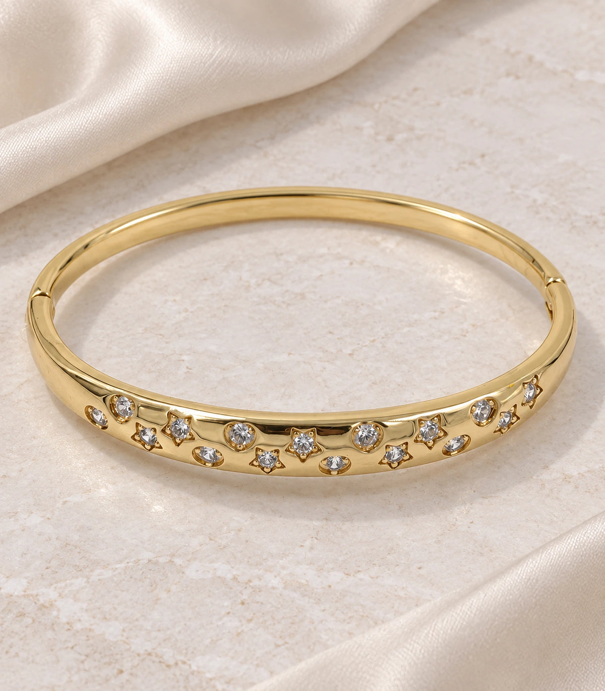 JIMIKI Gold-Tone Celestial Crystal Bangle — bangle in a styled flat lay #color_gold-tone / clear