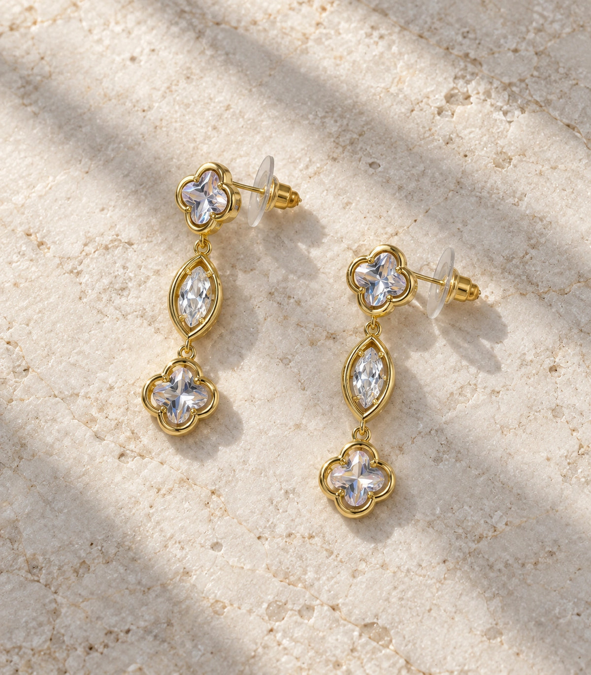 JIMIKI Clover Marquise Crystal Drop Earrings in Gold Tone, editorial flat lay #color_gold tone