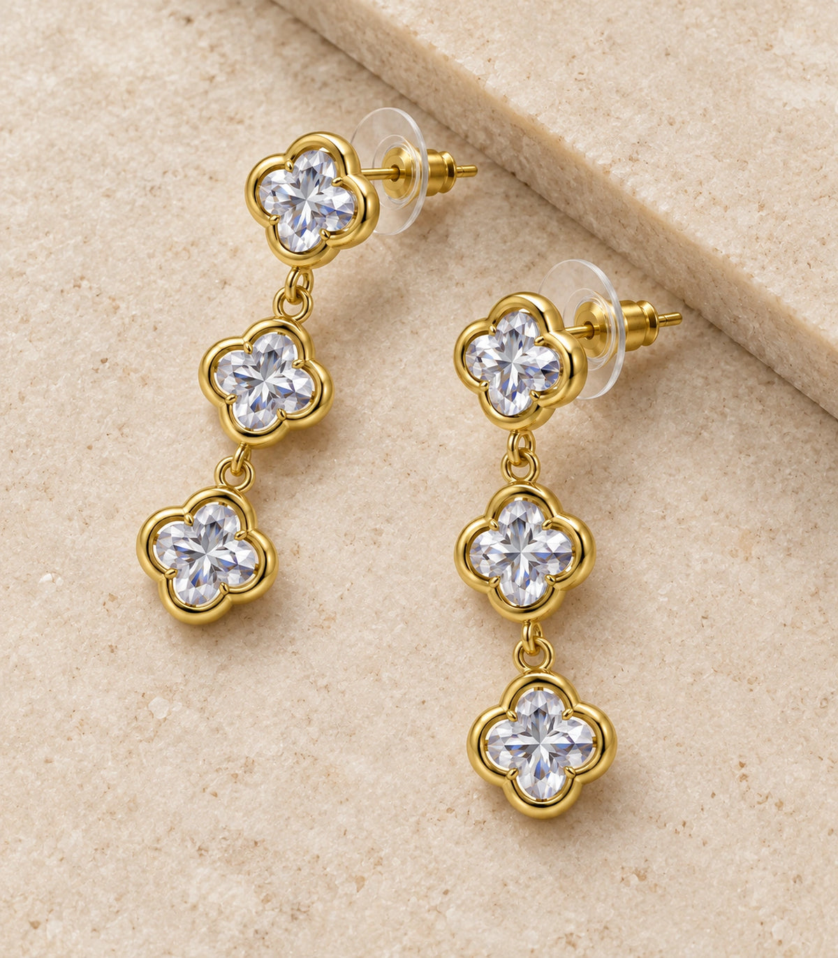 JIMIKI Triple Quatrefoil Crystal Drop Earring Pair in Gold tone / clear, editorial flat lay #color_gold tone / clear