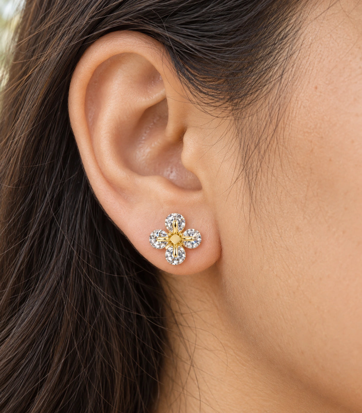 JIMIKI gold tone crystal flower stud earrings, worn closeup showing design details #color_gold-tone