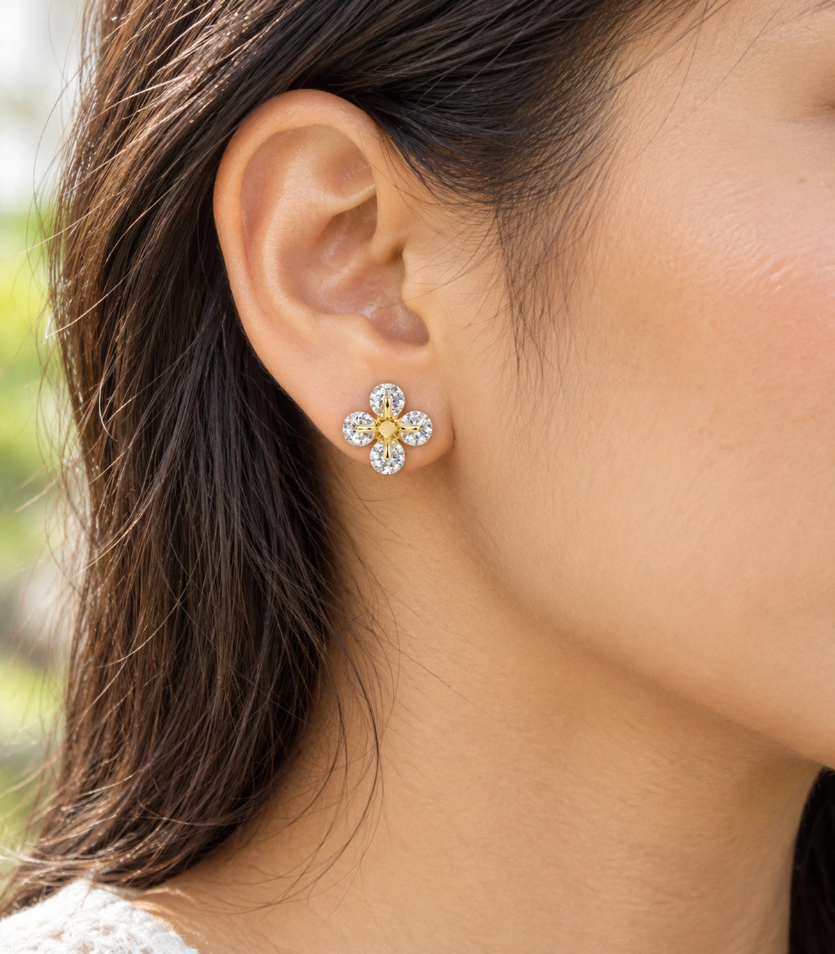 JIMIKI gold tone crystal flower stud earrings, shown worn on the ear #color_gold-tone
