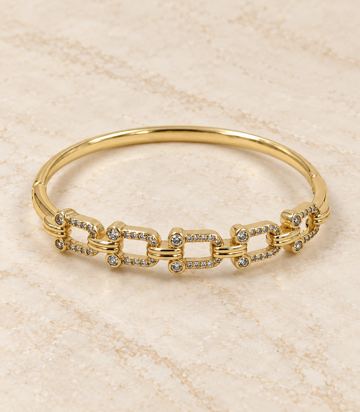 JIMIKI Gold-Tone Crystal Open Link Bangle — bangle in a styled flat lay #color_gold-tone / clear