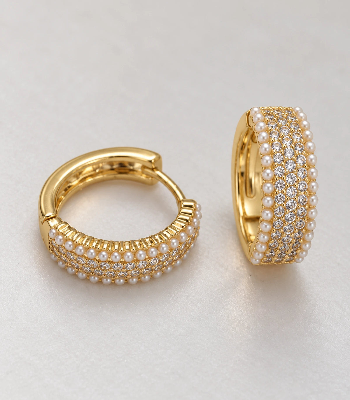 Close detail of the matching gold-tone huggie hoop pair with crystal-style rows and white pearl-style borders