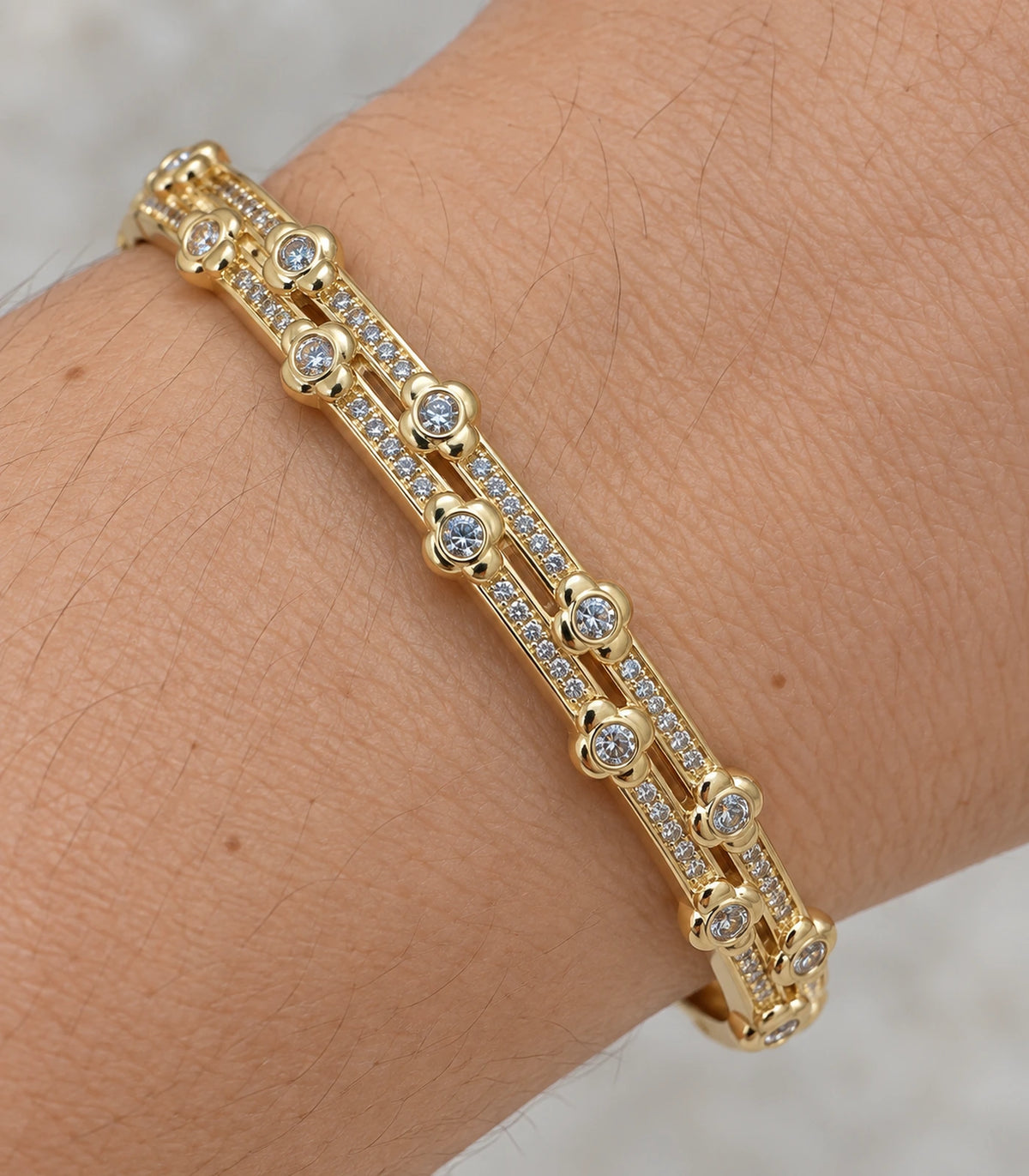 JIMIKI Gold-Tone Double Rail Bezel Crystal Bangle — close-up of the bangle worn on the wrist #color_gold-tone / clear