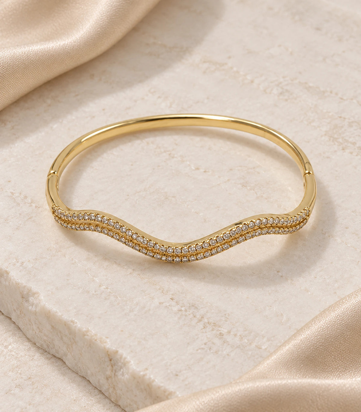 JIMIKI Gold-Tone Double Wave Pavé Bangle — bangle in a styled flat lay #color_gold-tone / clear