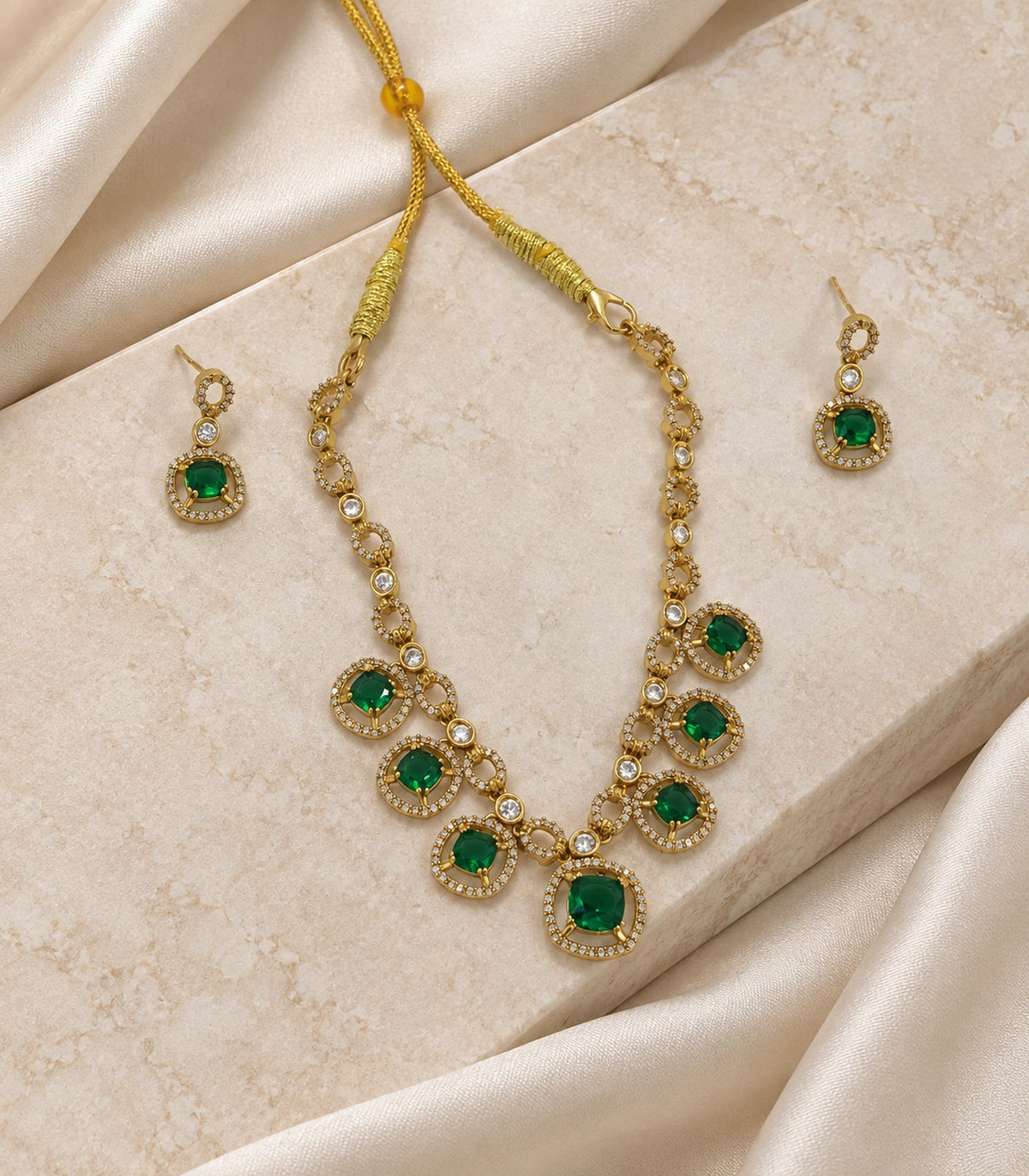 Round Crystal Teardrop Necklace Set in Emerald with gold-tone finish, editorial flat lay #Color_Emerald