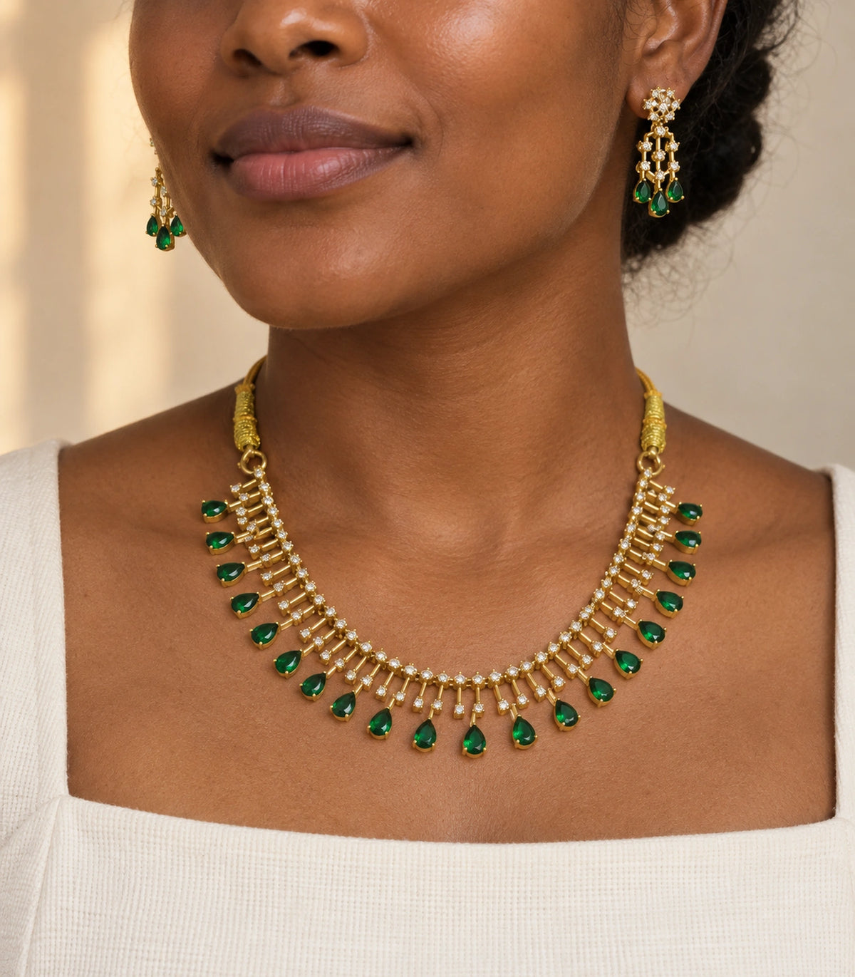Emerald-green teardrop fringe necklace and matching earrings shown worn with a white outfit #Color_Emerald