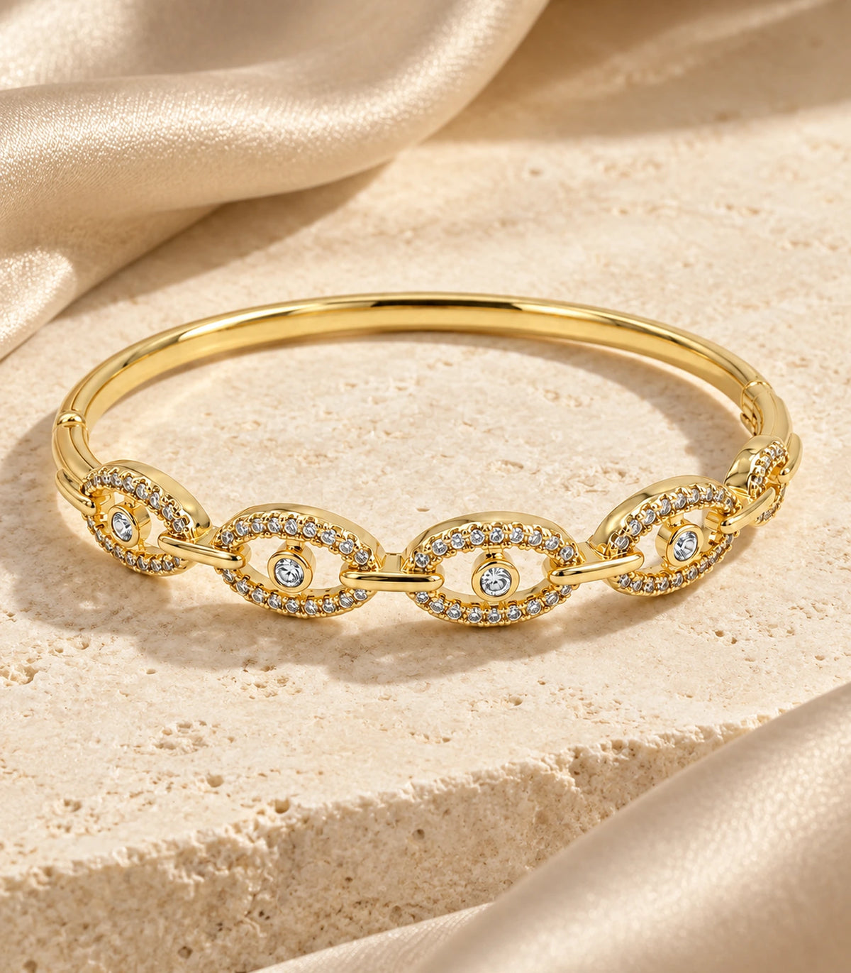 JIMIKI Gold-Tone Four Oval Halo Crystal Bangle — bangle in a styled flat lay #color_gold-tone / clear