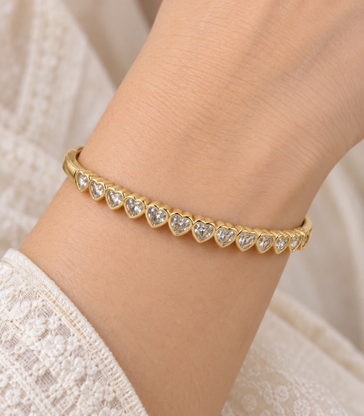 JIMIKI Gold-Tone Graduated Heart Crystal Bangle — close-up of the bangle worn on the wrist #color_gold-tone / clear