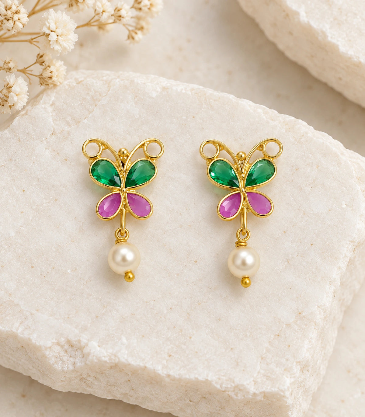 JIMIKI Green & Pink butterfly pearl drop earrings, pair arranged on a textured surface #color_green-pink
