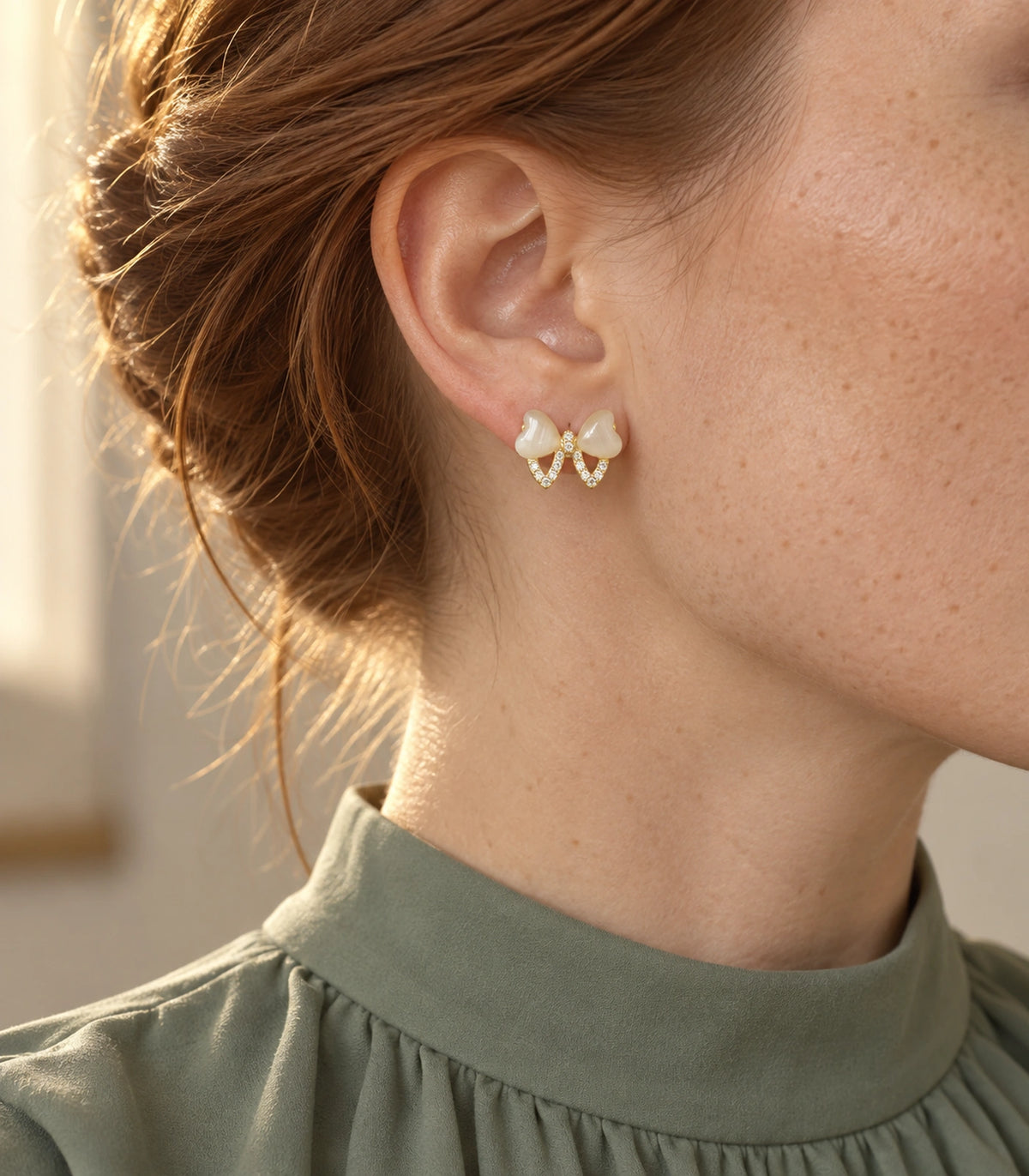 JIMIKI Gold Tone Ivory Heart Bow Crystal Stud Earring Pair in Gold tone, editorial model view