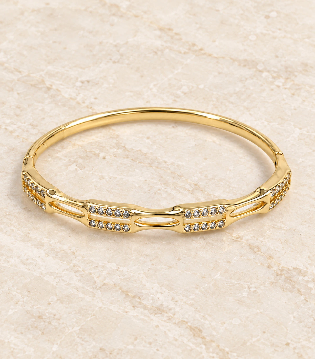JIMIKI Gold-Tone Open Link Double Row Crystal Bangle — bangle in a styled flat lay #color_gold-tone / clear