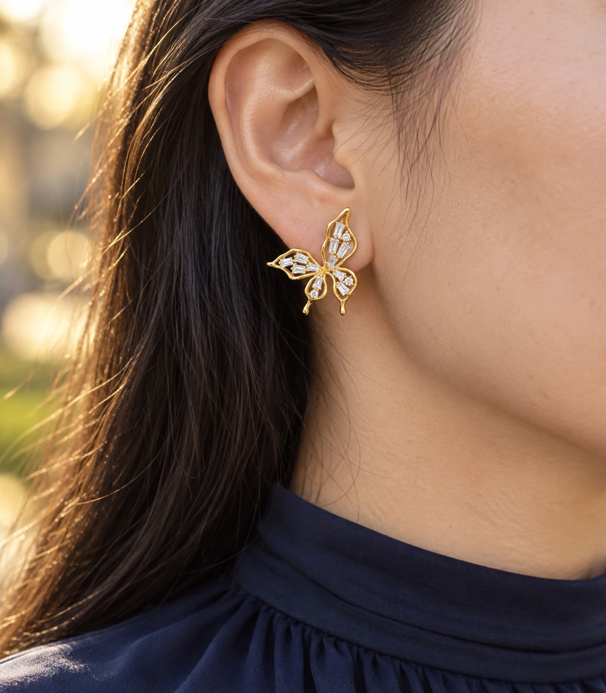 JIMIKI Openwork Baguette Crystal Butterfly Stud Earring Pair in Gold-tone, editorial model view #color_gold-tone