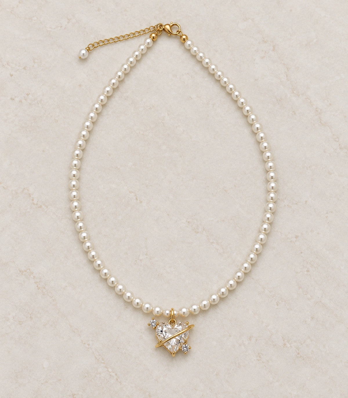 JIMIKI Gold Tone Orbit Heart Crystal Pearl Style Necklace in Gold tone / white, editorial flat lay