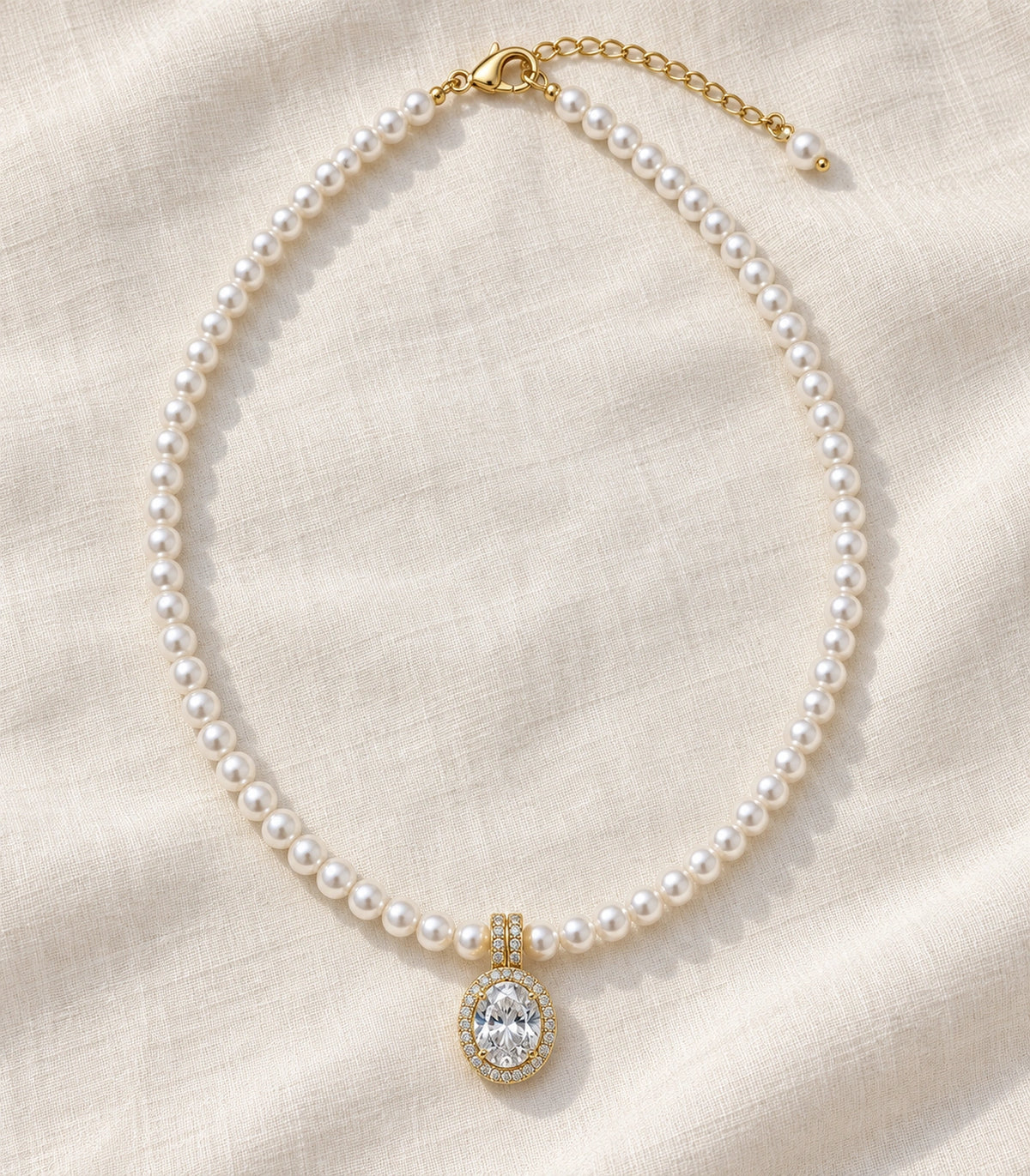 JIMIKI Gold Tone Oval Halo Crystal Pearl Style Necklace in Gold / White, editorial flat lay