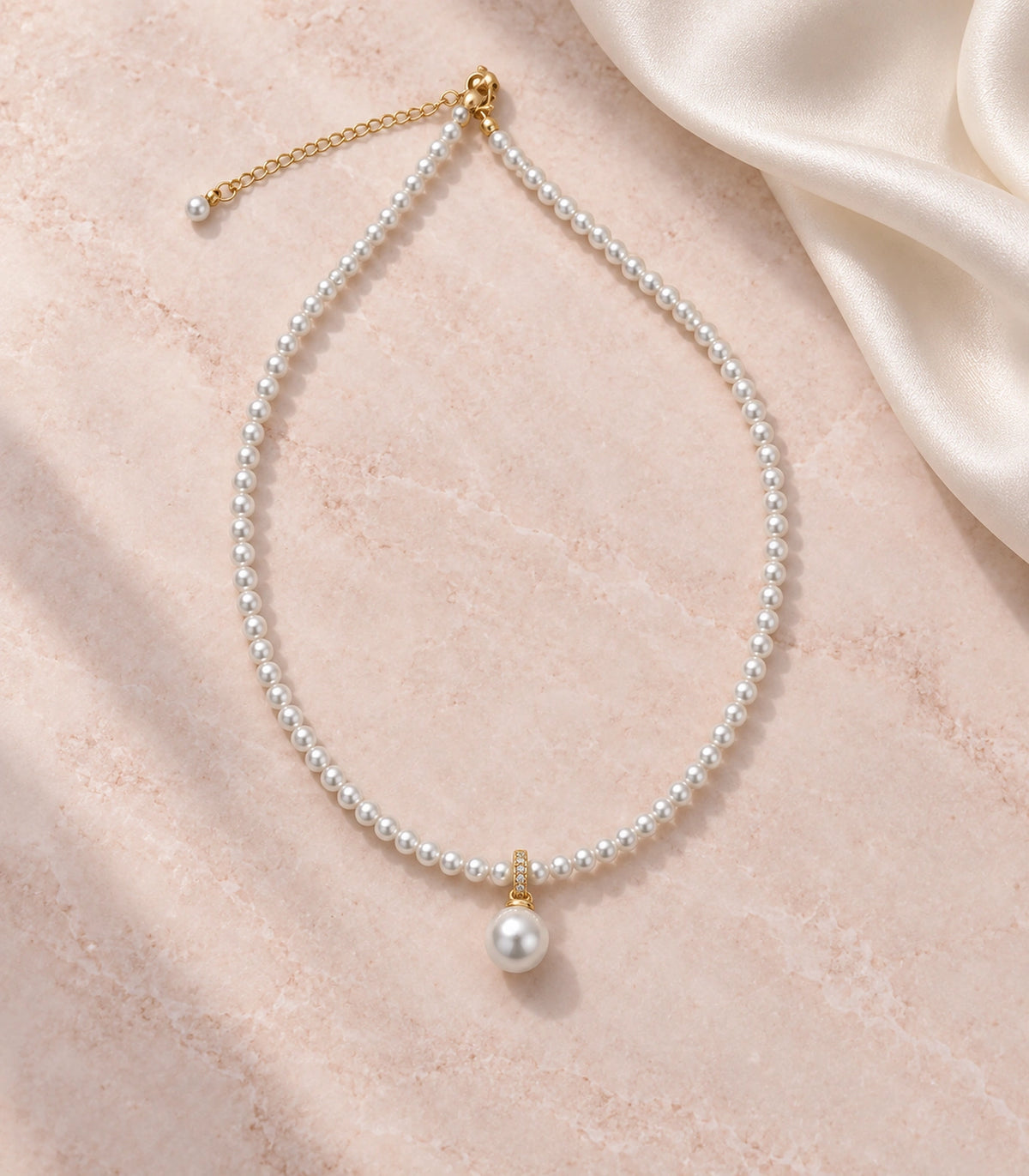 JIMIKI Gold-Tone Pavé Bail Pearl Drop Necklace in Gold-tone, arranged in an editorial flat lay