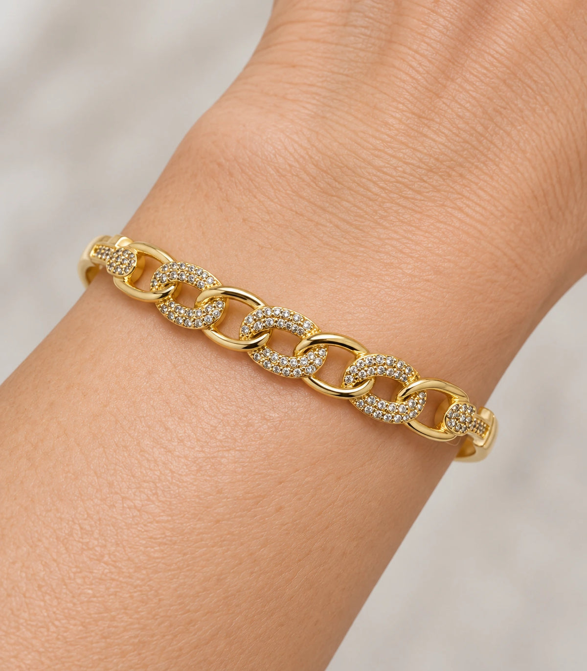 JIMIKI Gold-Tone Pavé Chain Link Bangle — close-up of the bangle worn on the wrist #color_gold-tone / clear
