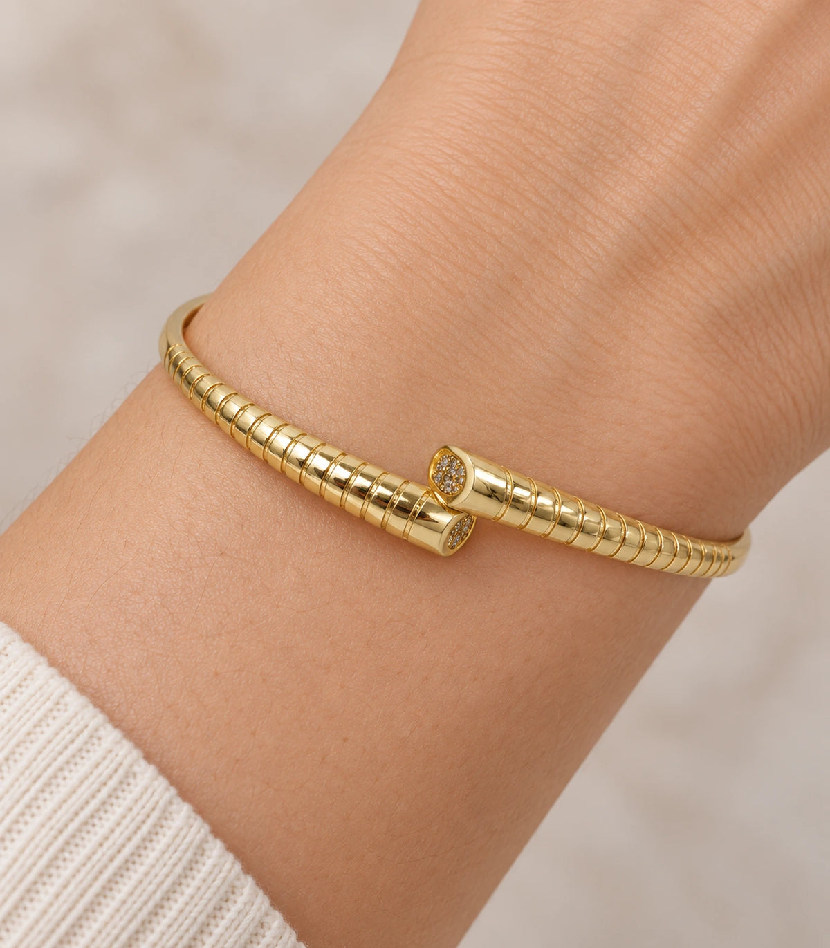 JIMIKI Gold-Tone Ribbed Pavé Tip Open Cuff Bangle — close-up of the bangle worn on the wrist #color_gold-tone / clear