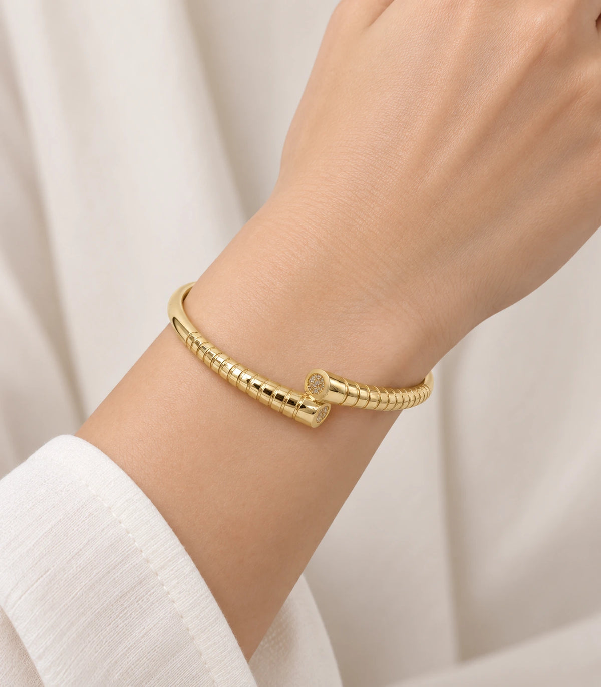 JIMIKI Gold-Tone Ribbed Pavé Tip Open Cuff Bangle — worn on the wrist #color_gold-tone / clear