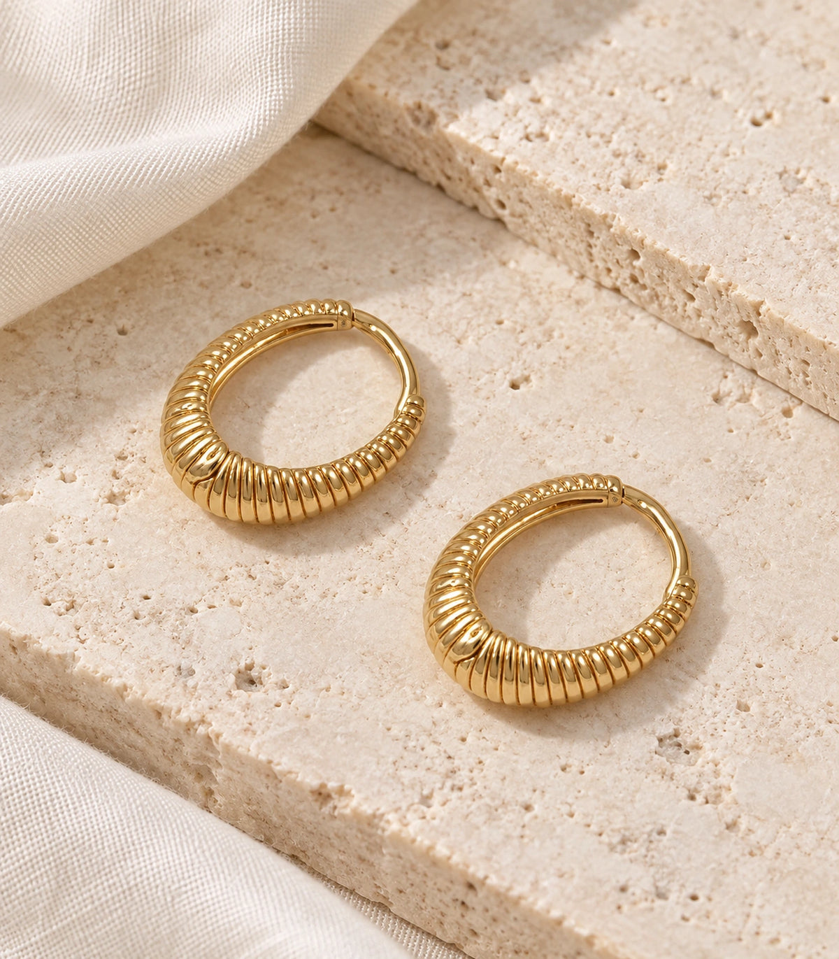 JIMIKI Ribbed Teardrop Hoop Earrings in Gold Tone - editorial flatlay #color_gold-tone