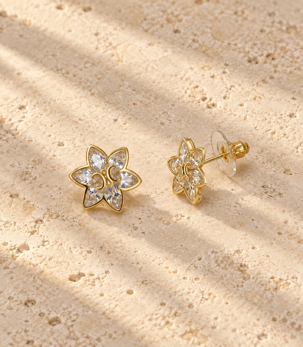 JIMIKI Gold-Tone Six-Petal Crystal Flower Stud Earrings in Gold / Clear, editorial flat lay