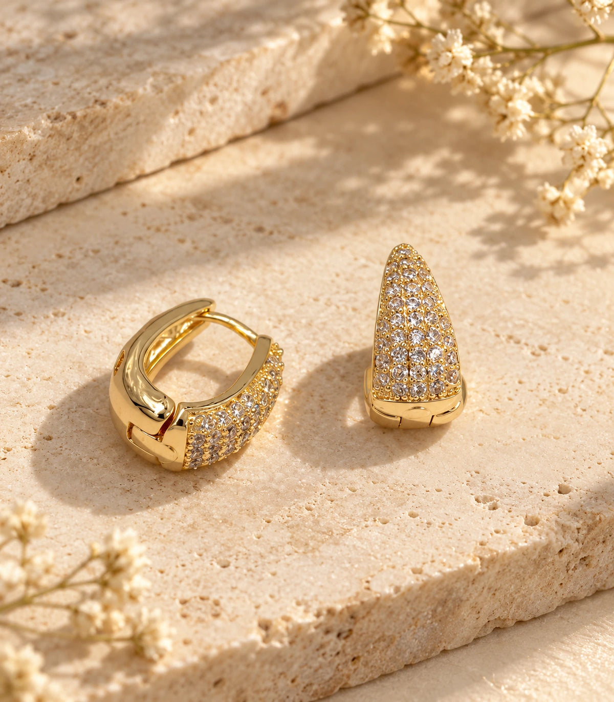 JIMIKI Gold Tone tapered pave huggie hoop earrings, pair styled on textured stone #color_gold-tone