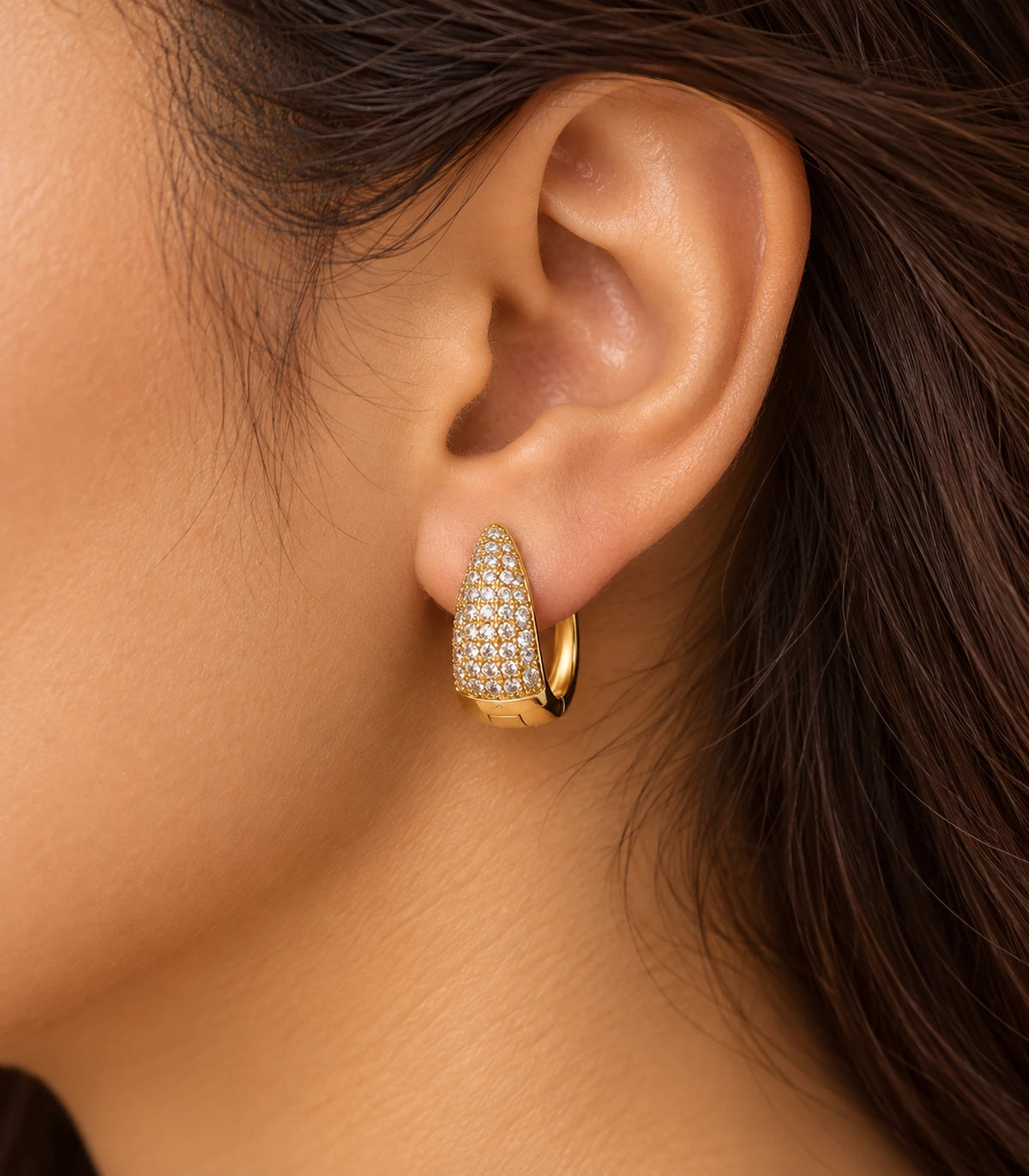 JIMIKI Gold Tone tapered pave huggie hoop earrings, worn in warm editorial lighting #color_gold-tone