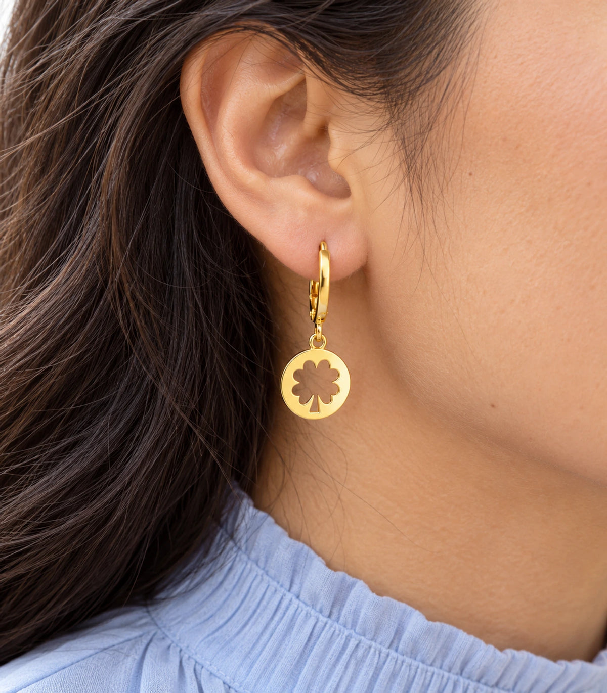 Gold-tone clover cutout hoop earring from the three-pair set in closeup