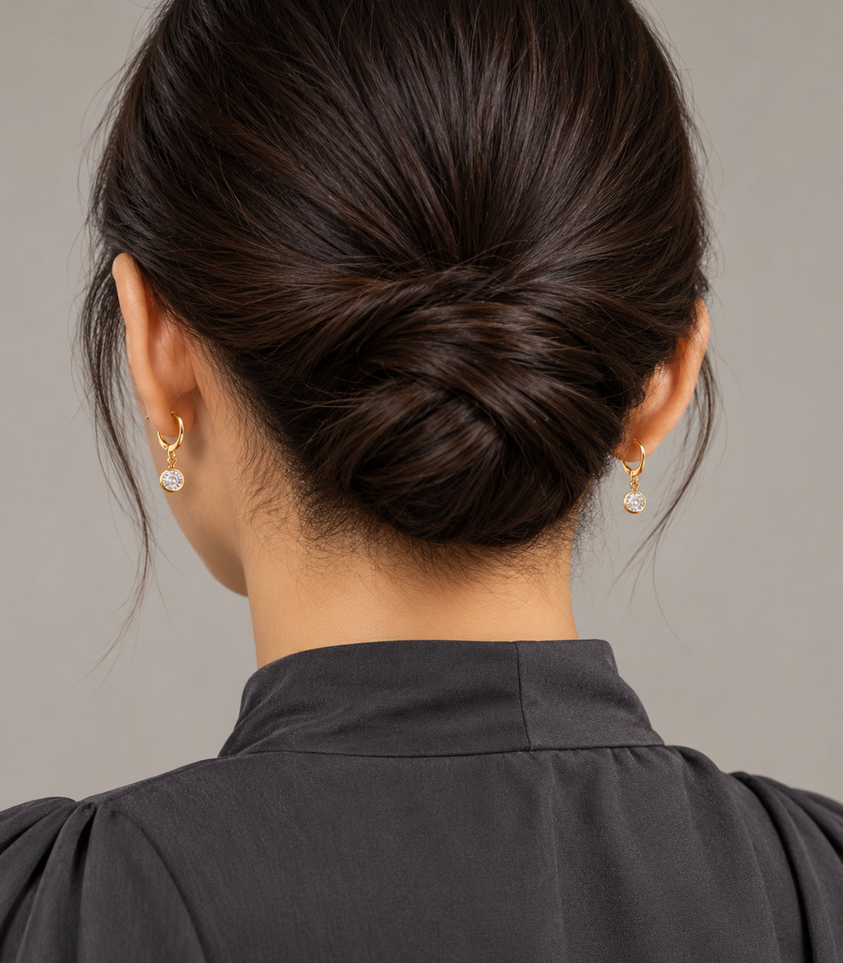 Gold tone clear crystal hoop earrings worn in a rear view