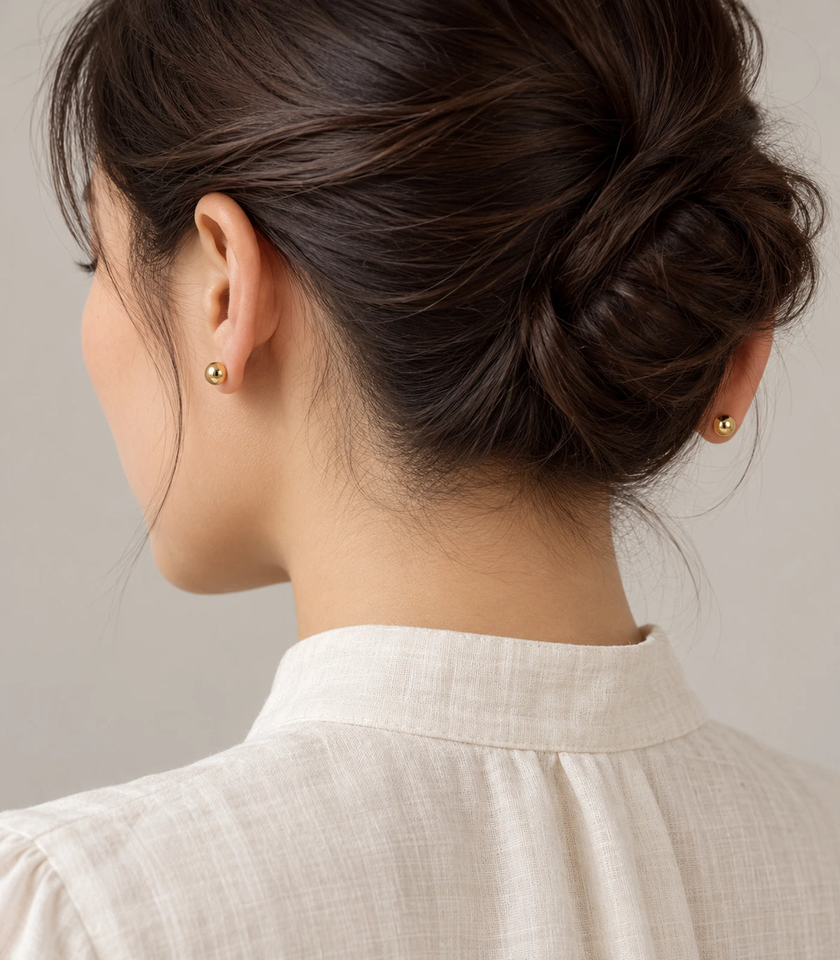 Gold-tone ball studs from the three-pair earring set, worn view